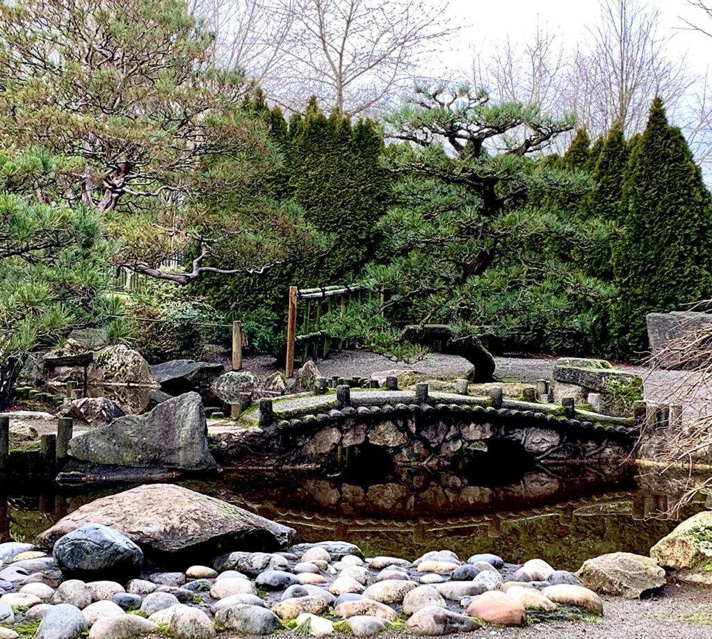 image of rock pathway with water and bridge in the distance