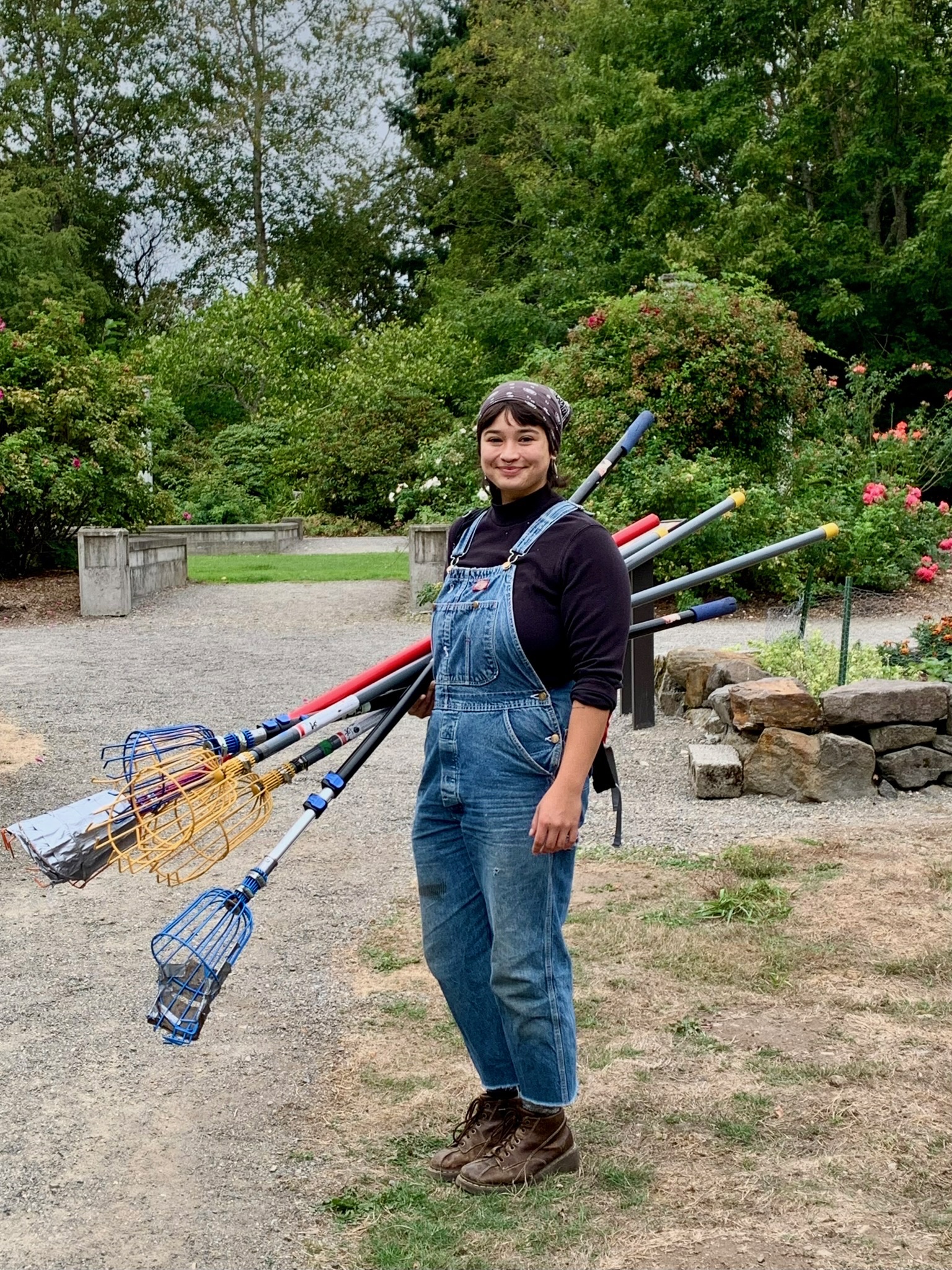 young woman with overalls carrying fruit picking tools in a garden